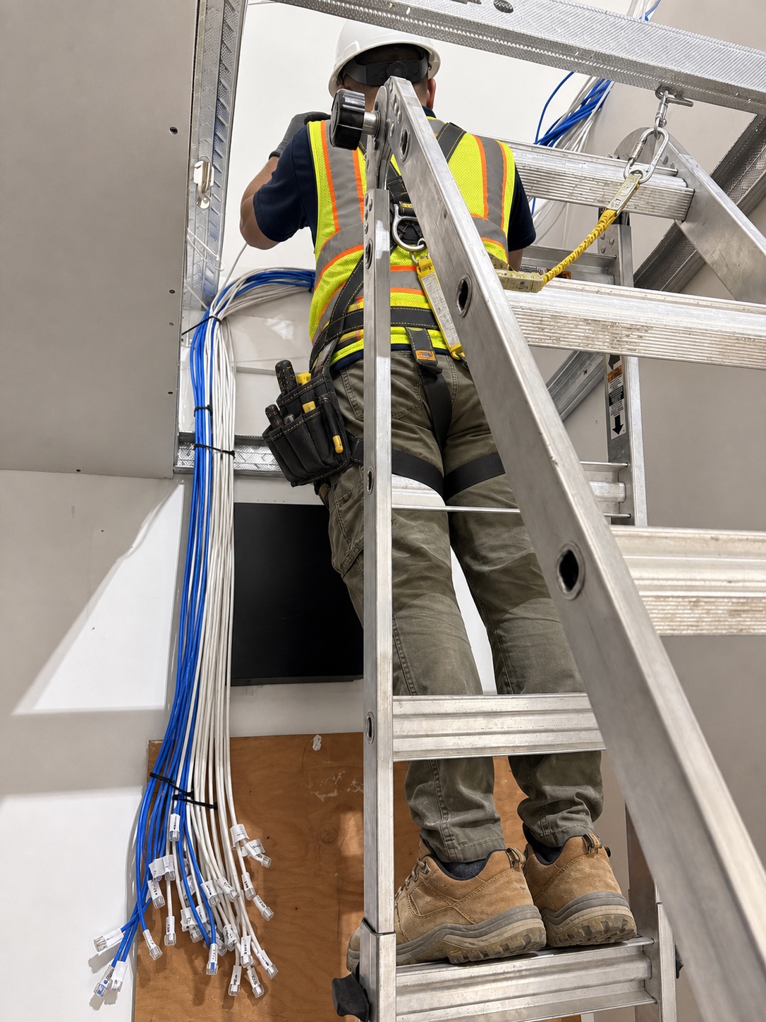 Technician routing structured cabling above a commercial ceiling